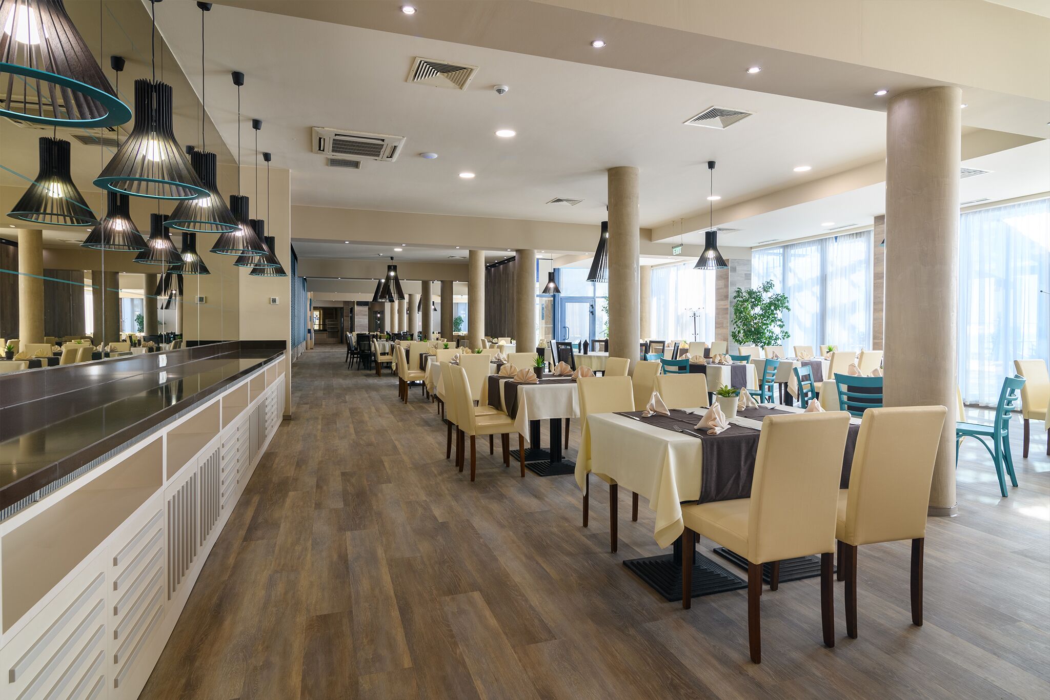 A spacious restaurant with high ceilings, modern pendant lighting, and a long counter.