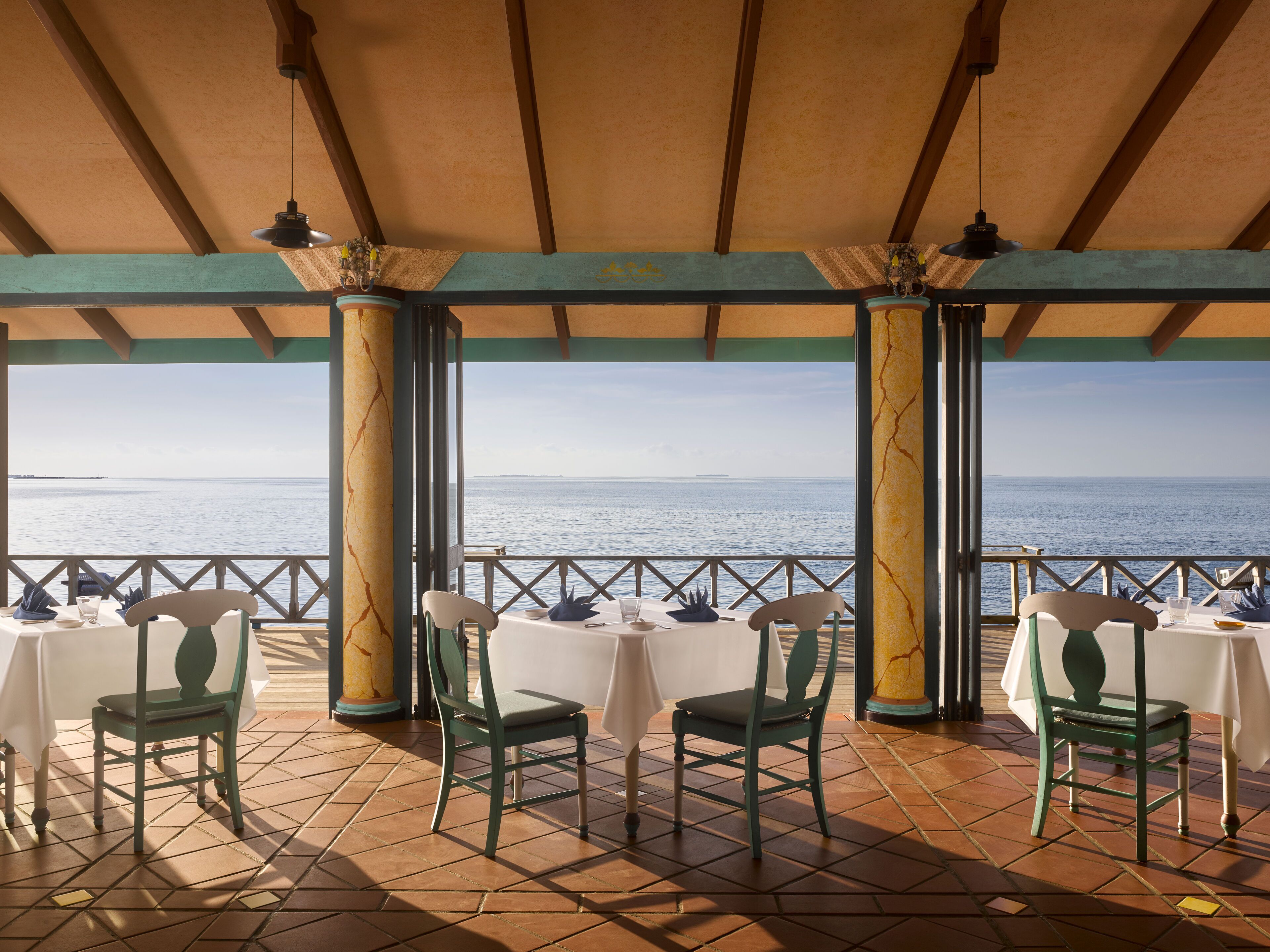 Una terraza con mesas y sillas, con vista al mar.