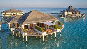 Overwater bungalows with private pools, clear blue water, and a view of the ocean.