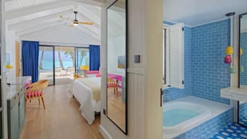 A room with a bed, a chair, a desk, and a large window overlooking the ocean.