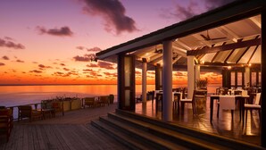 A restaurant with outdoor seating overlooking a sunset view.