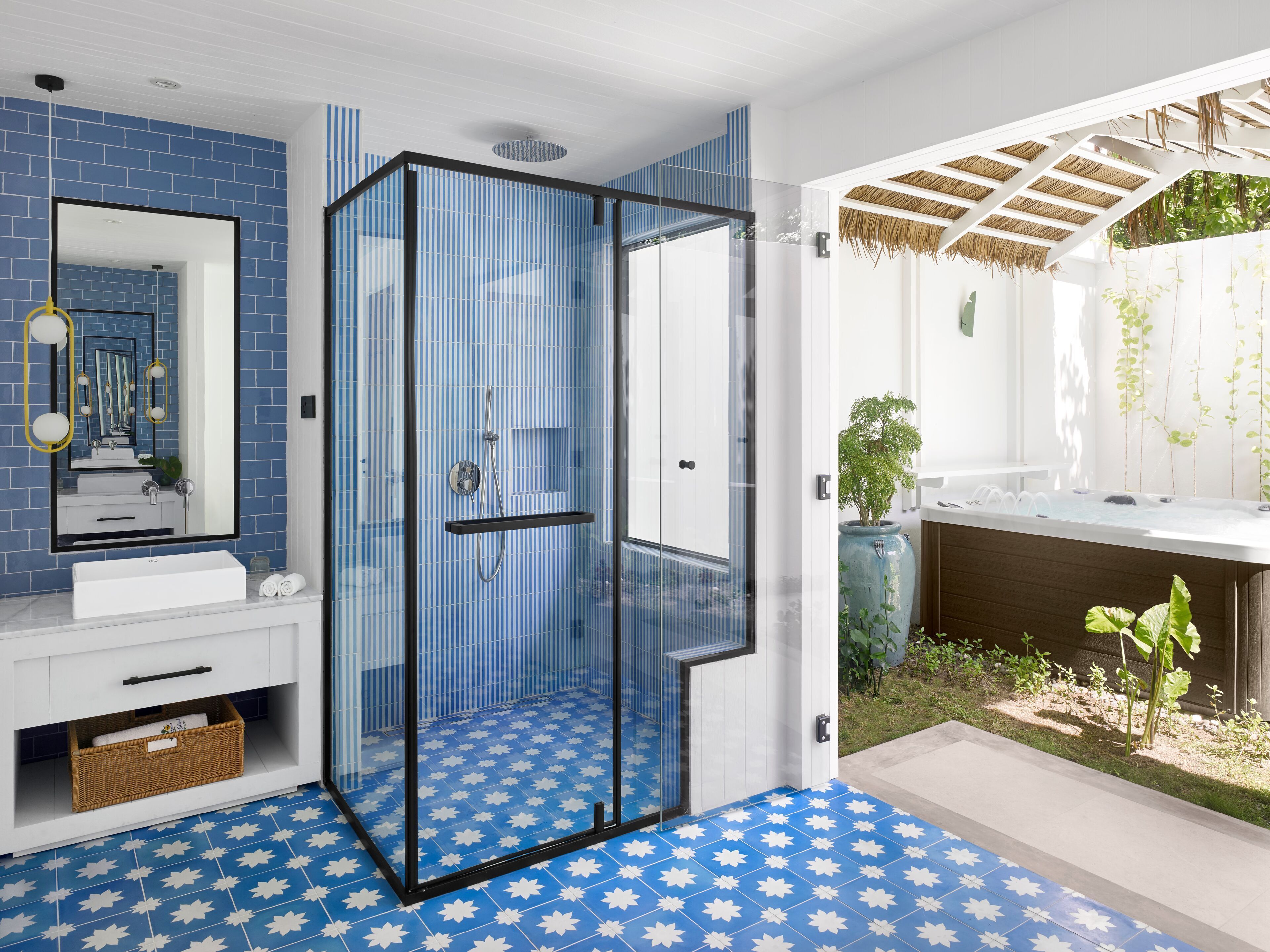 A modern bathroom with a glass-enclosed shower, a large mirror, and a white sink.