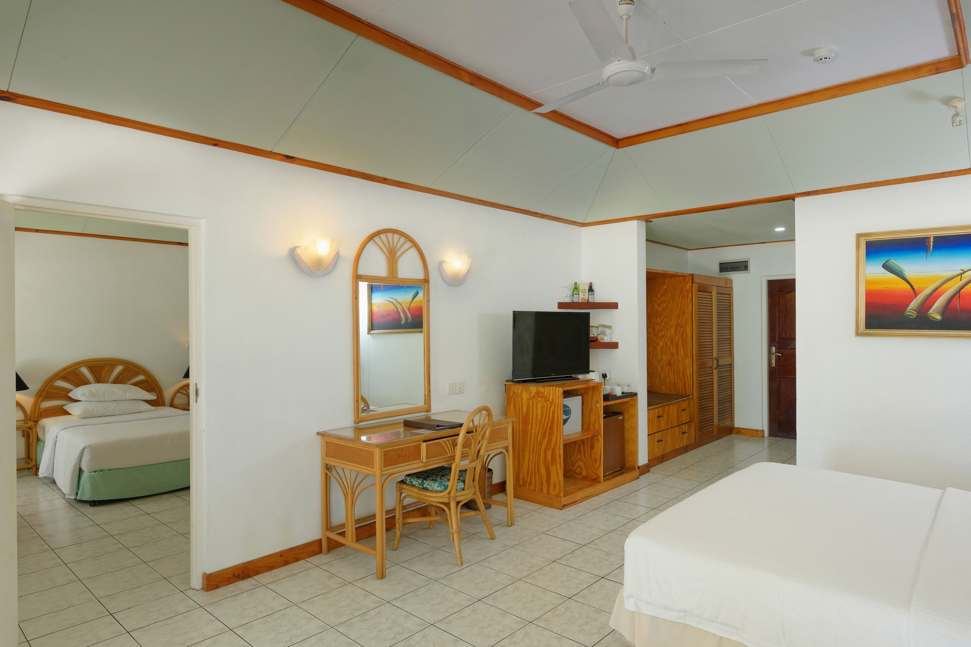 Una habitación de hotel con una cama, un escritorio con silla, un televisor y un armario.