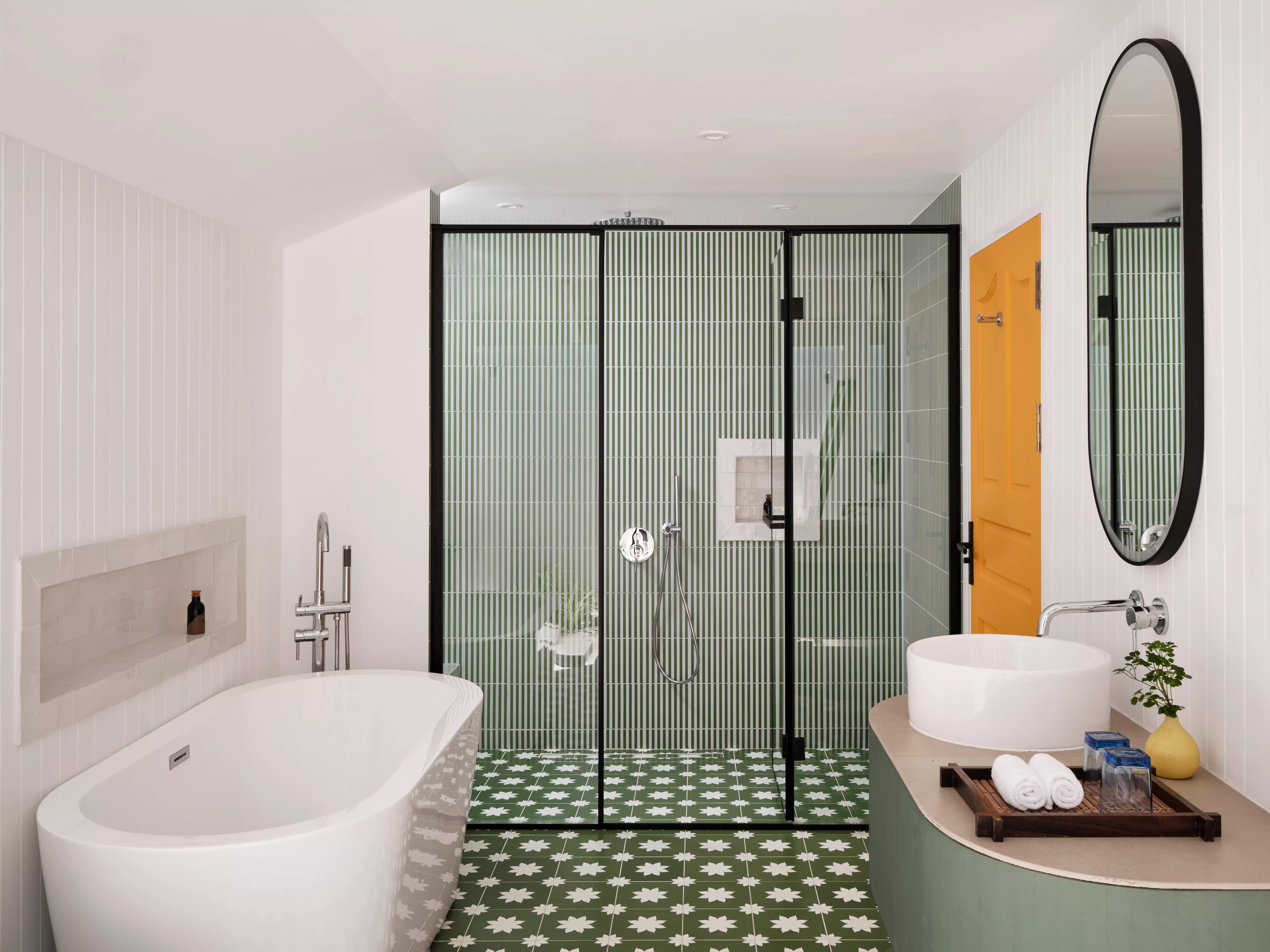 Un baño moderno con una bañera independiente, una ducha con mampara de vidrio y un lavamanos con espejo.