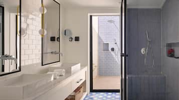 Une salle de bain moderne avec un grand miroir, un meuble-lavabo blanc et un espace douche aux carreaux rayés.