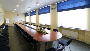 A conference room with a long table, chairs, a whiteboard, and large windows with blue blinds. - Sputnik (Minsk)