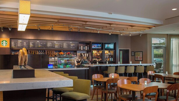 A modern bar area with a menu board, seating, and a Starbucks logo. - Courtyard by Marriott Nashville Goodlettsville (Goodlettsville)