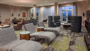 A hotel lobby with multiple seating areas, including sofas and armchairs, arranged around a central coffee table. - Courtyard by Marriott Nashville Goodlettsville (Goodlettsville)