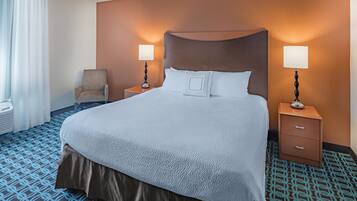 Ein Hotelzimmer mit einem großen Bett, zwei Nachttischen mit Lampen, einem Sessel und einem Teppich mit Muster.