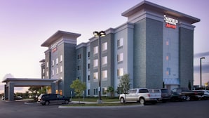 Een Fairfield Inn & Suites by Marriott hotel met een modern ontwerp, meerdere verdiepingen en een parkeerplaats met verschillende voertuigen.