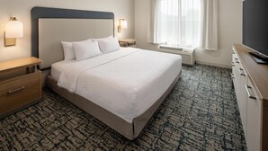 A hotel room with a large bed, bedside tables, a TV, a window with curtains, and a patterned carpet. - Homewood Suites by Hilton Minneapolis/St. Paul-New Brighton (New Brighton)