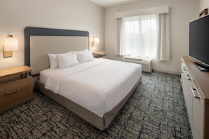 A hotel room with a large bed, bedside tables, a TV, a window with curtains, and a patterned carpet. - Homewood Suites by Hilton Minneapolis/St. Paul-New Brighton (New Brighton)