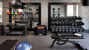 Un gimnasio con equipo de ejercicio, incluyendo cintas de correr, kettelbells y mancuernas.