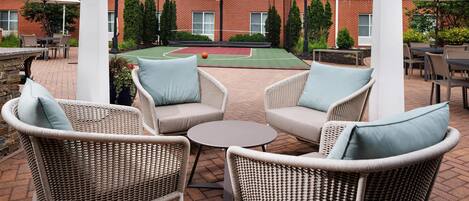 A patio area with wicker furniture, a small round table, and a basketball court.