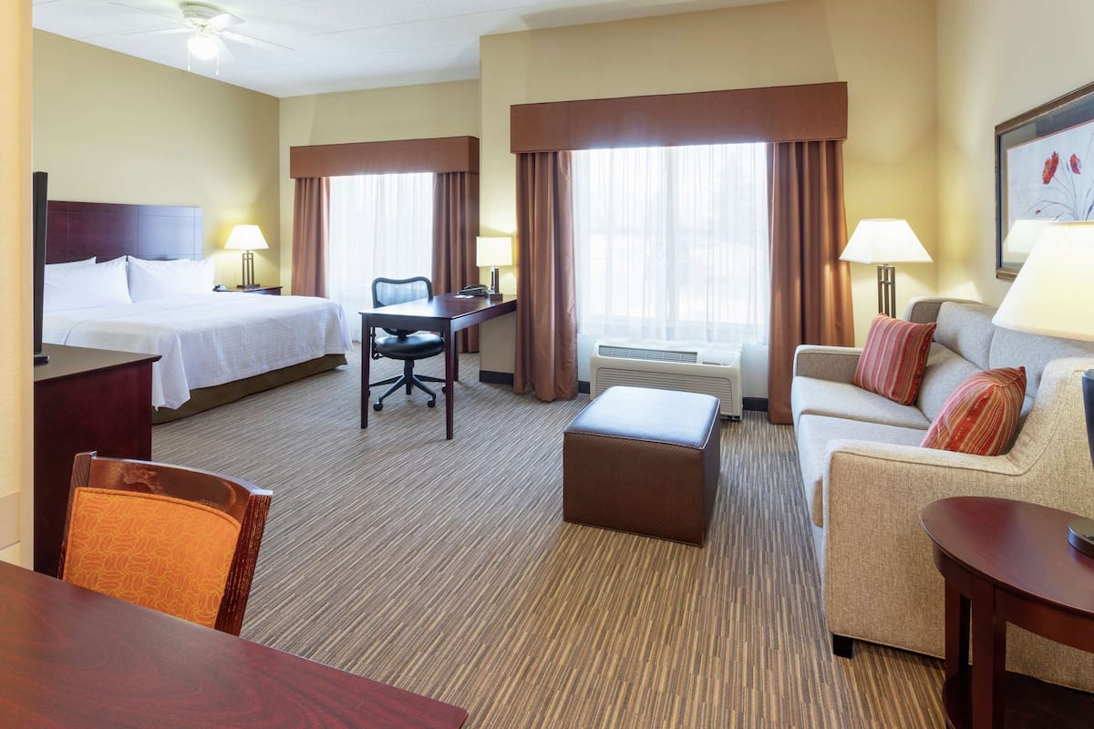 A hotel room with a bed, a desk, a sofa, and a chair.