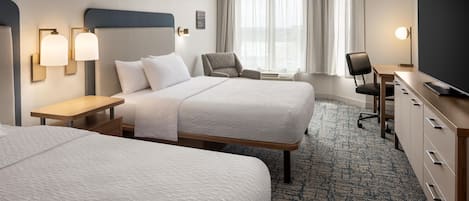 A hotel room with two beds, a desk, a chair, a television, and a window with curtains.