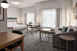 Una habitación de hotel con cama, escritorio, silla, sofá y una mesita.