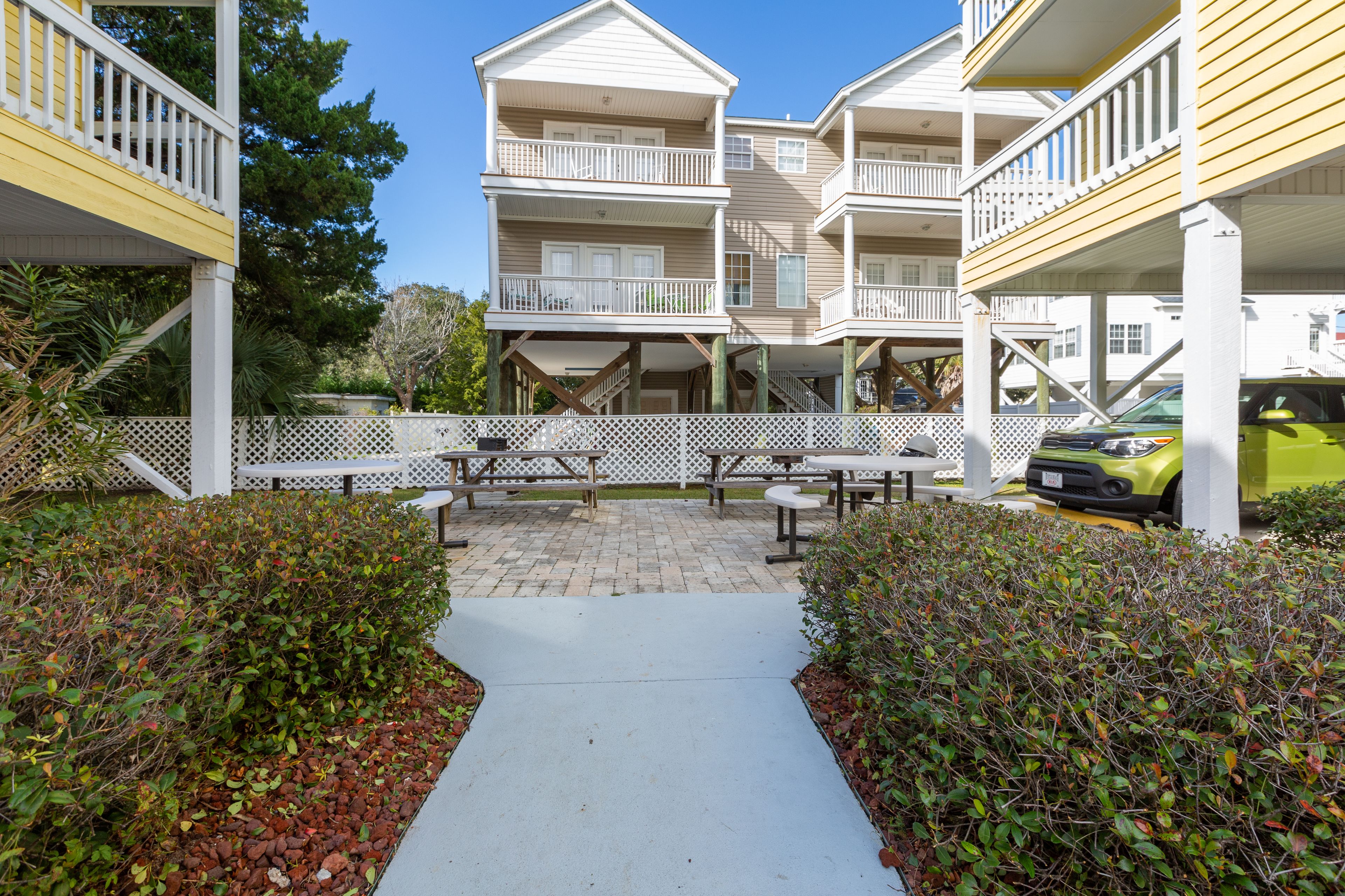 A multi-story building with balconies, outdoor seating, and a paved walkway.