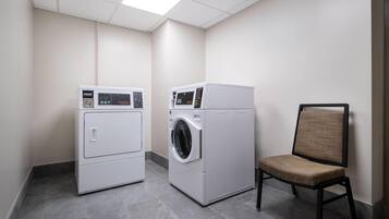 A laundry room with two washing machines and a chair.