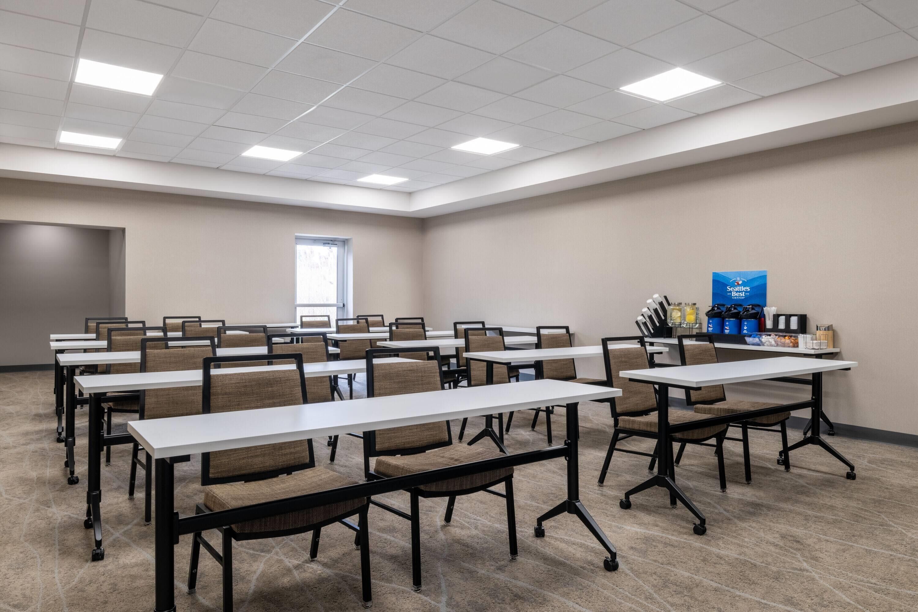 Une salle de conférence équipée de plusieurs tables et chaises, d’une fenêtre et d’une porte.