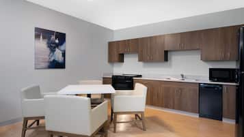 Una cocina moderna con armarios de madera, un refrigerador negro, lavavajillas y una mesa de comedor blanca con sillas.