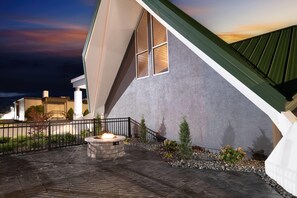 A modern building with a unique sloped roof, a fire pit, and a landscaped patio area. - Wingate by Wyndham Geneva at SPIRE Academy (Geneva)