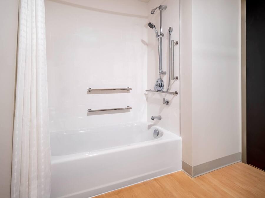 A white bathtub with grab bars, a showerhead, and a faucet.