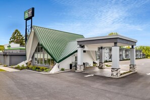 A modern building with a green roof, a covered waiting area, and a signboard. - Wingate by Wyndham Geneva at SPIRE Academy (Geneva)