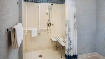 Un espace douche équipé d’un banc, d’un porte-serviettes et d’un pommeau de douche.