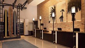 A reception area with a brick wall, palm tree artwork, and surfboards on display.