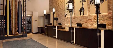 A reception area with a brick wall, palm tree artwork, and surfboards on display.