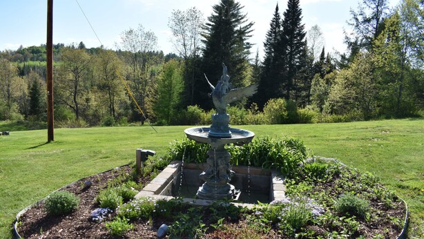A garden with a central fountain, surrounded by a circular stone border. - The Barron Brook Inn (Whitefield)