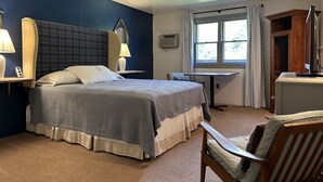 A hotel room with a large bed, a desk, a chair, a window with curtains, and a television.