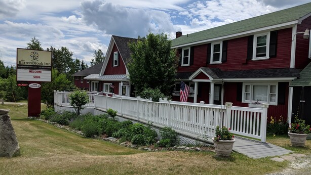 A red building with a white porch and a signboard.