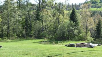 A grassy field with a stone structure and trees in the background.