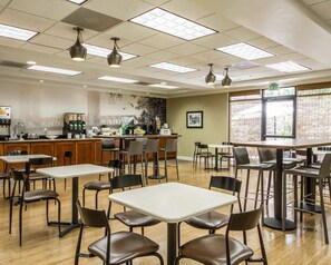 A restaurant with multiple tables and chairs, a bar area, and a view through large windows. - Hotel Med Park, an Ascend Collection Hotel (Sacramento)