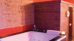 Un moderno cuarto de spa con una bañera de hidromasaje rectangular grande, paneles de pared de madera y piso de baldosas.