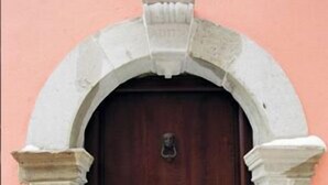 Una puerta de madera oscura con un aldabón de latón, ubicada en un arco de piedra.