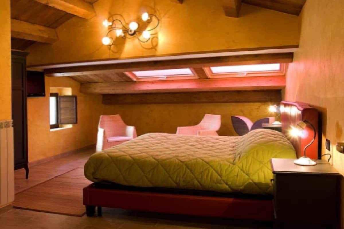 A bedroom with a bed, a desk, and a chair. There is a window and a ceiling light fixture.