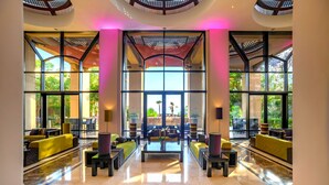 A spacious lobby with a central seating area, large windows, and a modern ceiling design.