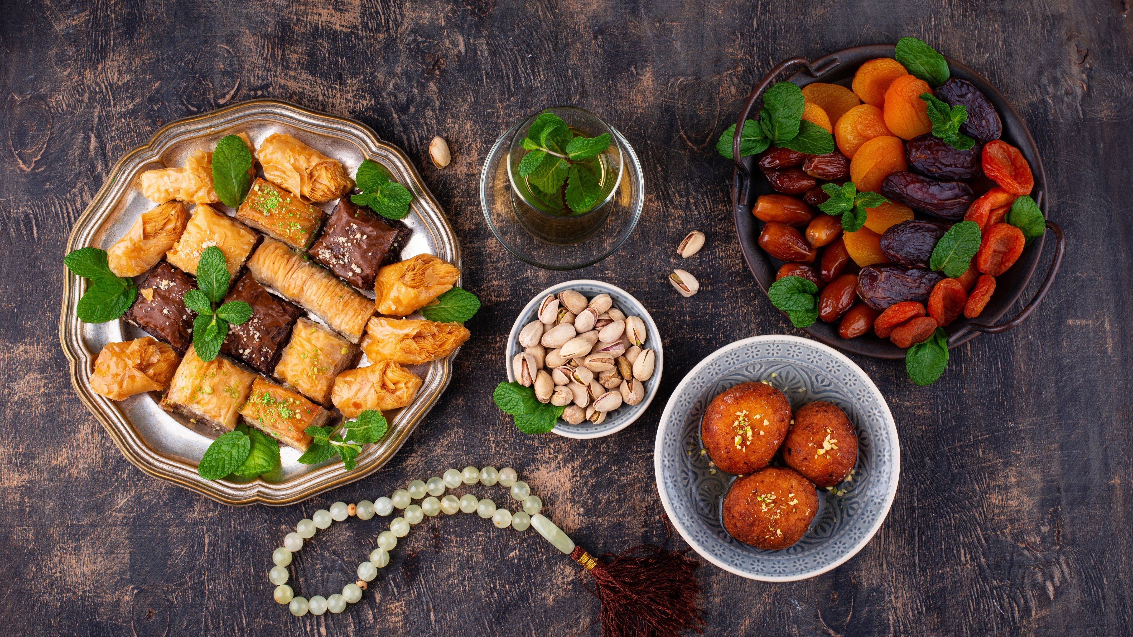 A variety of food items including pastries, nuts, and dried fruits arranged on a wooden surface.