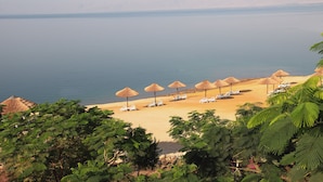 A beach with thatched umbrellas and lounge chairs. - Holiday Inn Resort Dead Sea by IHG (Sweimeh)