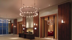 A modern hotel lobby with a large circular chandelier, wooden paneling, and a reception desk with a potted plant. - Hyatt Regency Hong Kong, Tsim Sha Tsui (Kowloon)