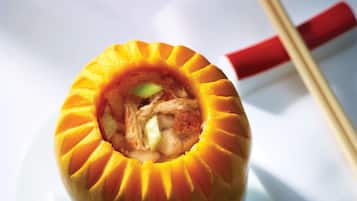 A bowl of soup with chopsticks and a napkin on a white table.