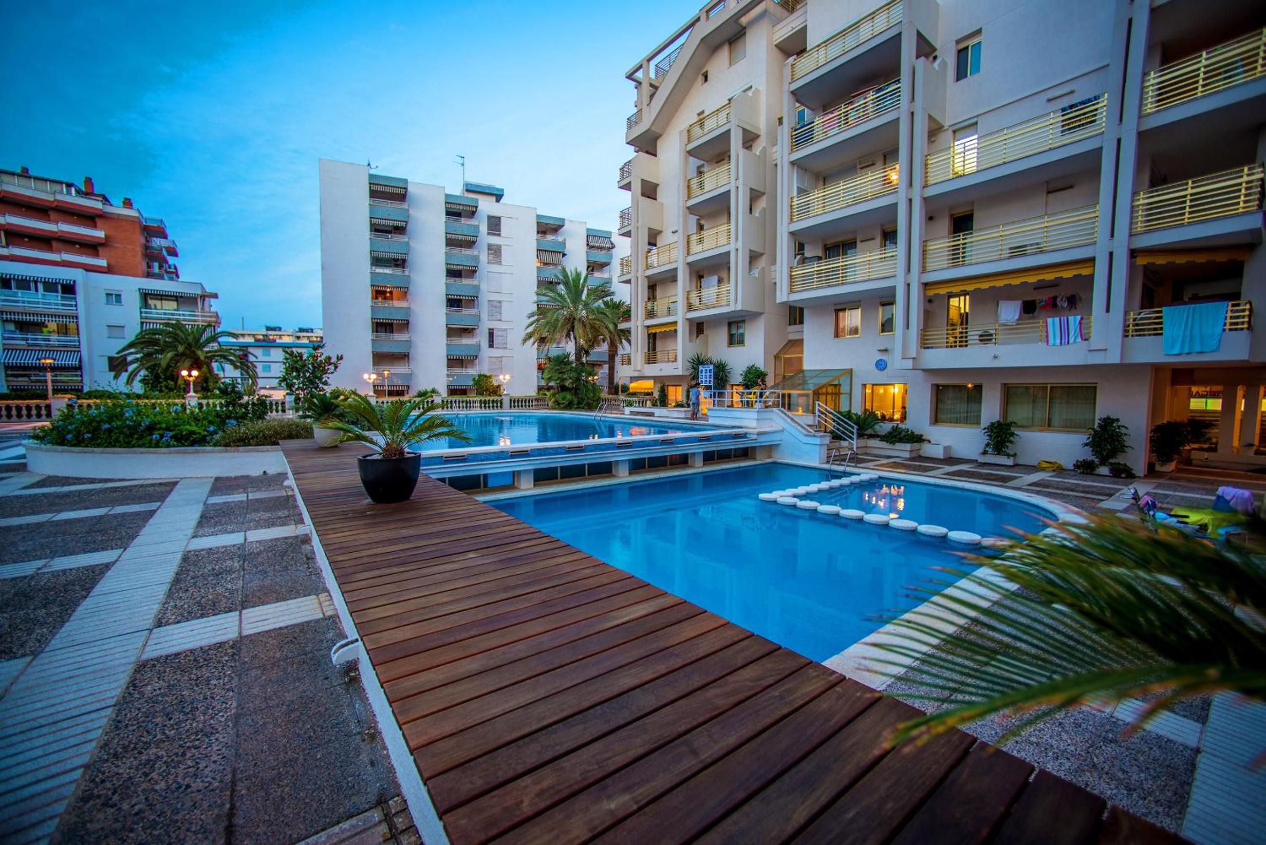 Un hôtel doté d’une piscine, d’une terrasse en bois et de plusieurs balcons.