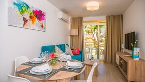 A dining area with a table set for six, a teal sofa, and a colorful abstract painting on the wall. - Ona Suites Salou (Salou)