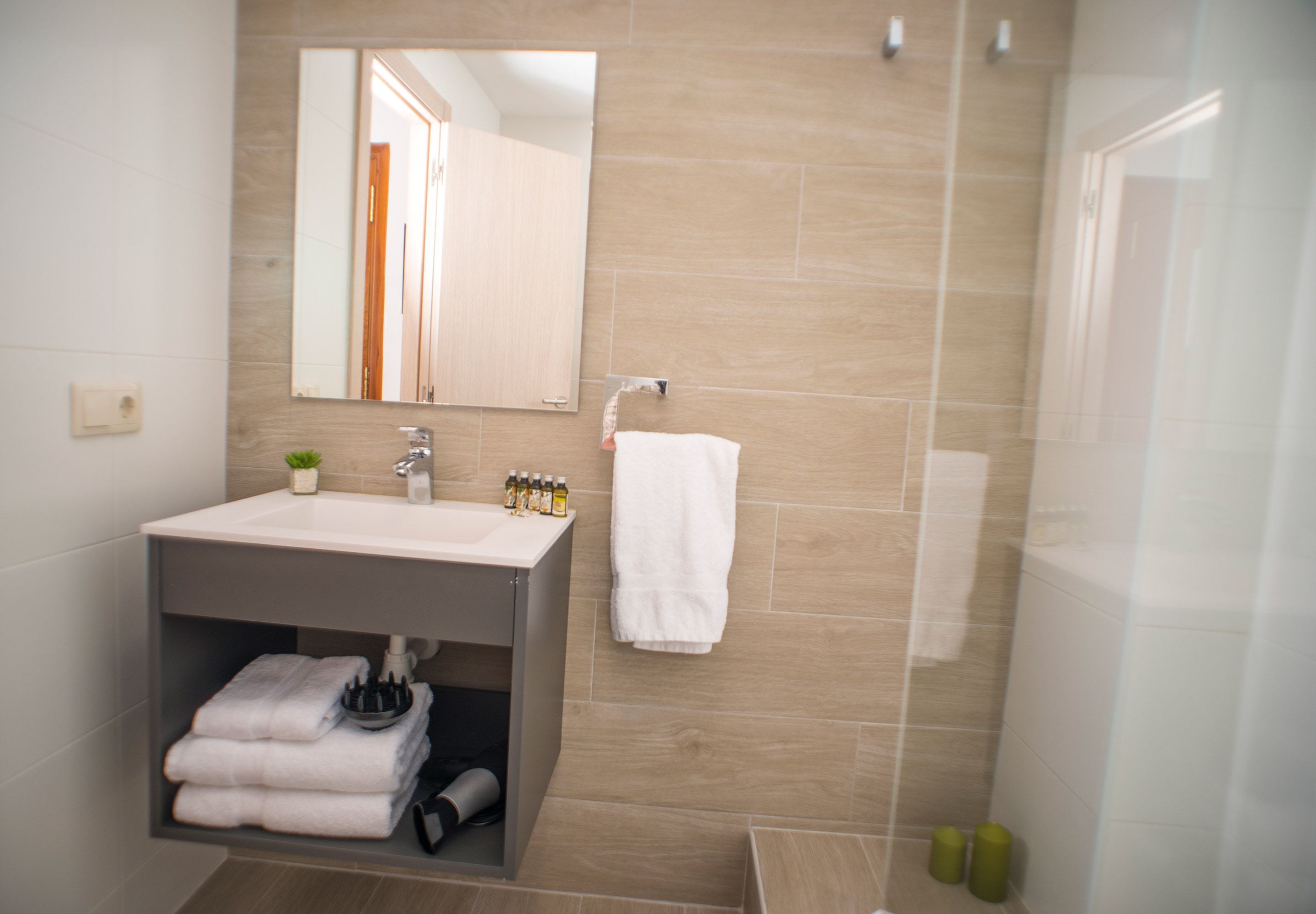 Un baño con lavabo, espejo y perchero para toallas.