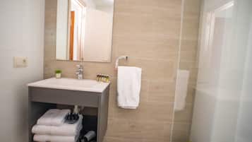 Un baño con lavabo, espejo y perchero para toallas.