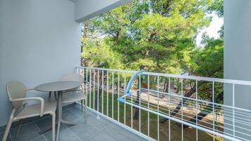 Enjoy a peaceful retreat with a balcony offering a serene view of lush greenery and a clear sky.