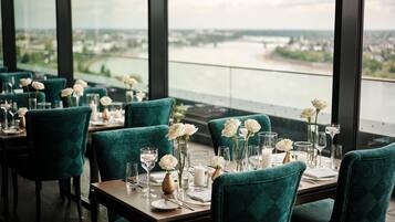 A restaurant with tables set for dining, featuring teal chairs and white flowers.